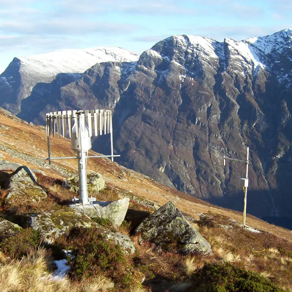 Geonor T-200B nedbørmåler med vindskjerm i fjellside over fjorden